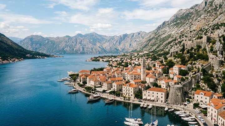 Pogled na kameni barokni grad Perast sa zvonikom crkve Svetog Nikole i ostrvima u zalivu
