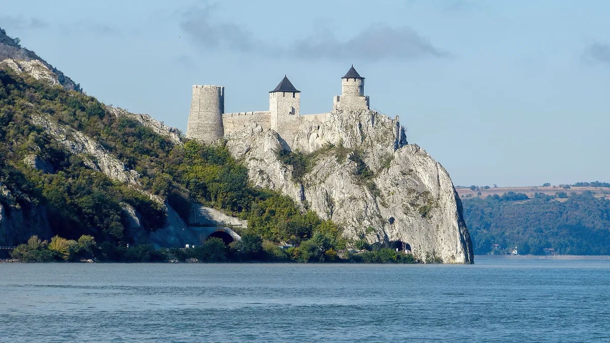 Srebrno jezero u smiraj dana sa uređenom peščanom plažom i jedrilicama na mirnoj vodi