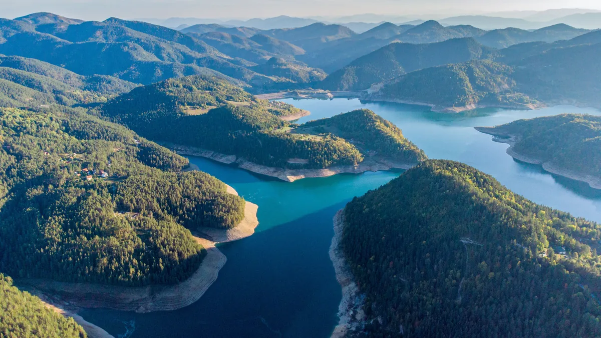 Smaragdno Vlasinsko jezero sa plutajućim tresetnim ostrvom obraslim brezama pod planinskim vrhovima